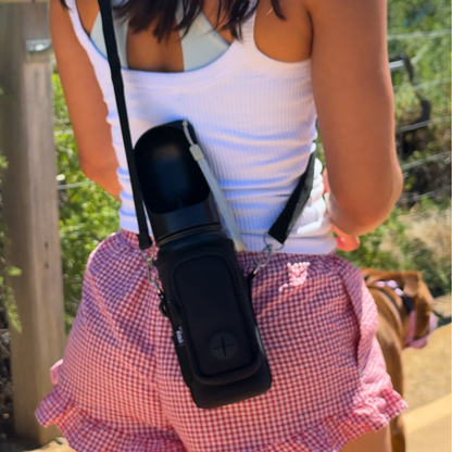 Person wearing a white tank top and pink checkered shorts with a black dog water bottle holder.