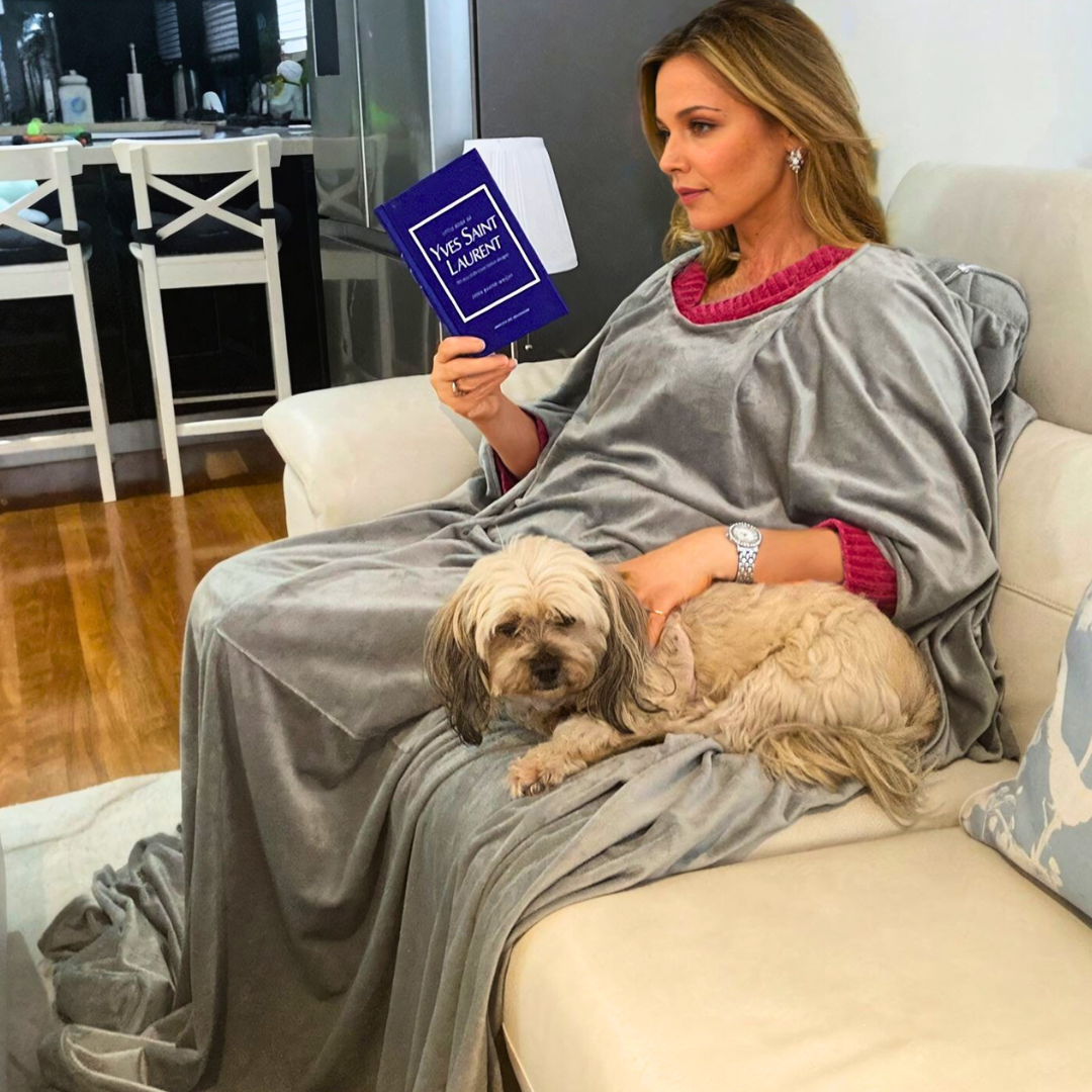 Woman using wearable blanket with pillow sat with dog